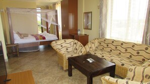 A hotel room with a bed, a sofa, a coffee table, and a desk.