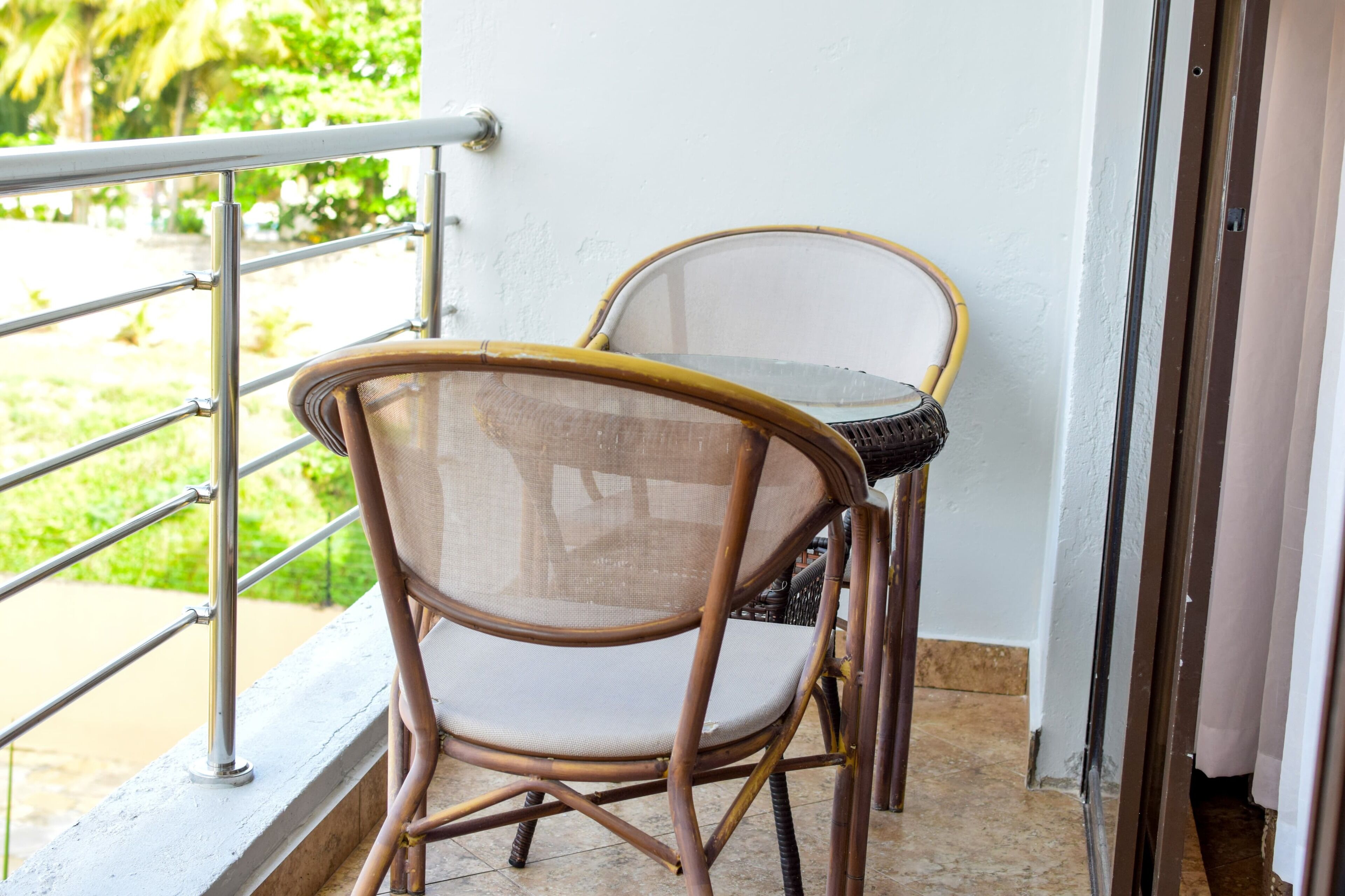 A balcony with a metal railing, a wicker chair, and a table.