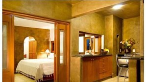 A hotel room with a bed, a desk, and a chair. There is a door leading to another room. - Hotel Valle Místico (Tepoztlán)