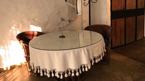 A round table with a white tablecloth and a lace border, a metal candelabra, a chair, and a rustic wooden door. - Hotel Valle Místico (Tepoztlán)