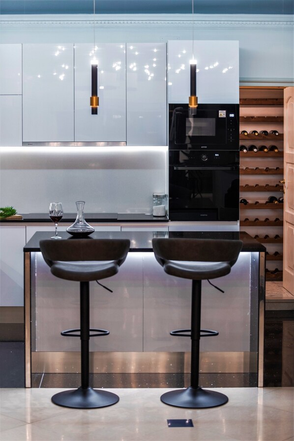 A modern kitchen with two bar stools, a wine glass, and a wine rack.