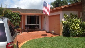 A residential house with a garage, a patio with two chairs, and an American flag. - 3 bedroom house w/private heated salt water pool, bbq, quiet location  (Pembroke Pines)