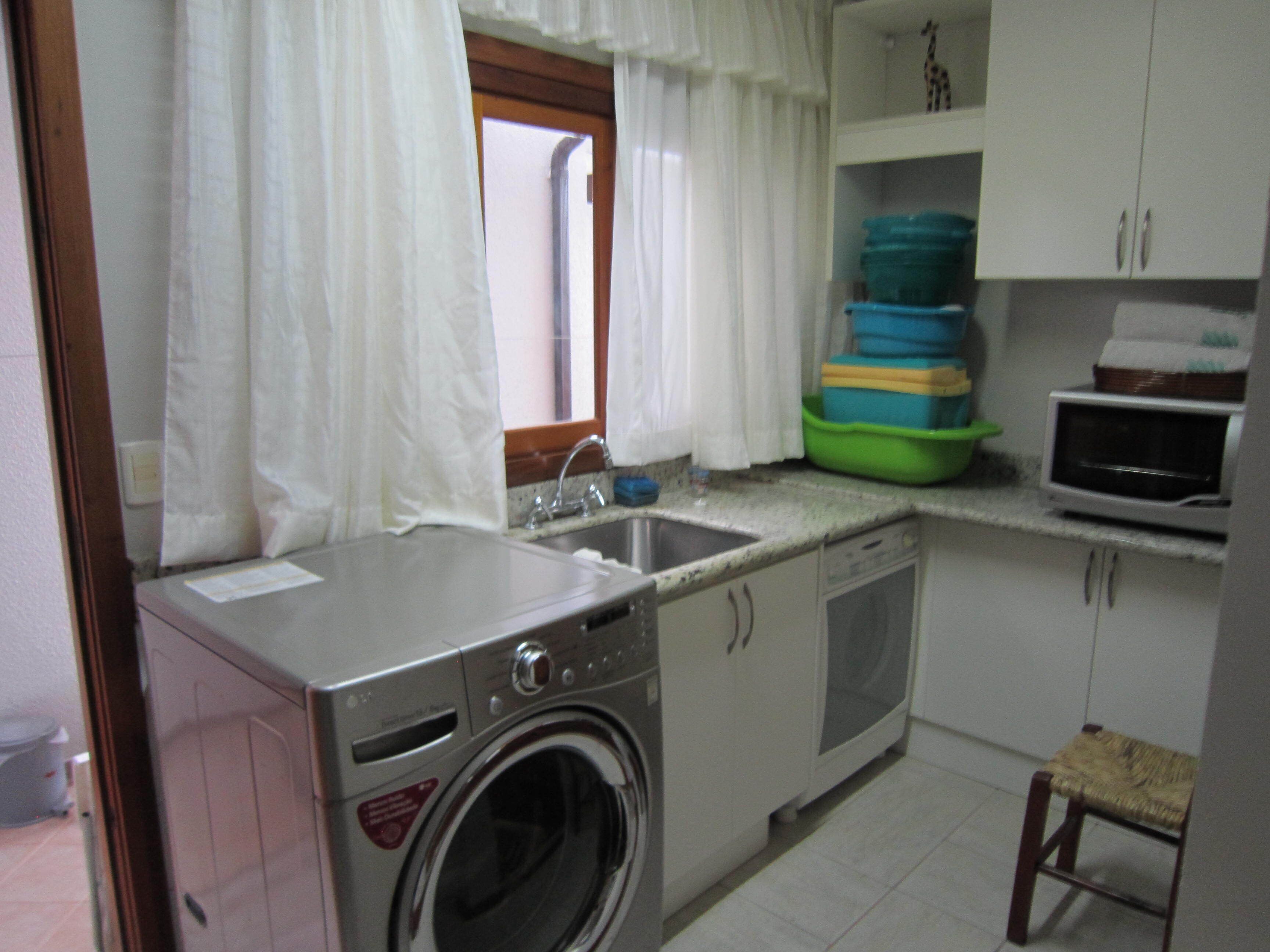 Une cuisine compacte équipée d’un lave-linge, d’un évier et d’un four à micro-ondes.