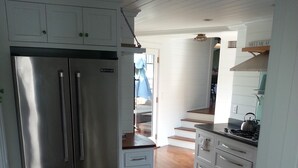 A modern kitchen with stainless steel appliances, wooden flooring, and white cabinetry. - Chatham Village - Center - Main Street Center Area (Chatham)