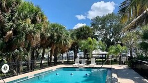 A swimming pool surrounded by palm trees and a fenced area with lounge chairs. - NEW COMPLETE REMODEL, MELBOURNE HARBOUR VIEWS (Melbourne)