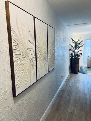 A hallway with a wooden floor, a wall-mounted decorative panel, and a potted plant. - NEW COMPLETE REMODEL, MELBOURNE HARBOUR VIEWS (Melbourne)