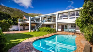 A two-story house with a swimming pool, a covered patio, and a staircase leading to the upper level.