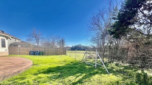 Ein Garten mit Rasenfläche, einem Metallzaun und einem Haus im Hintergrund.