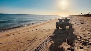 Una playa con huellas que conducen a un vehículo.