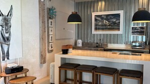 Una cocina moderna con barra, taburetes de madera y un cuadro de un ciervo.