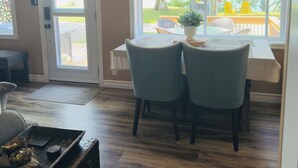 Un coin repas comprenant une table et des chaises, un ventilateur de plafond et une vue sur une terrasse avec des sièges à l’extérieur.