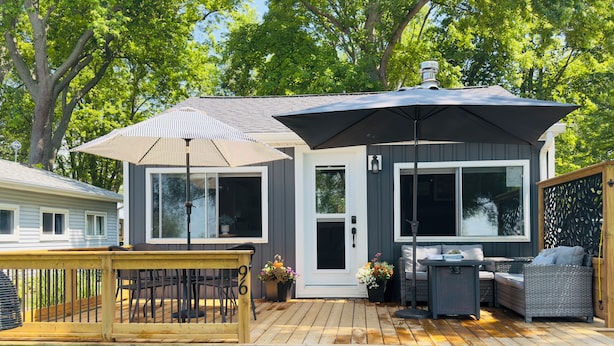 Une terrasse dotée de mobilier d’extérieur, d’un patio couvert et offrant une vue sur une maison avec de grandes fenêtres et une porte.