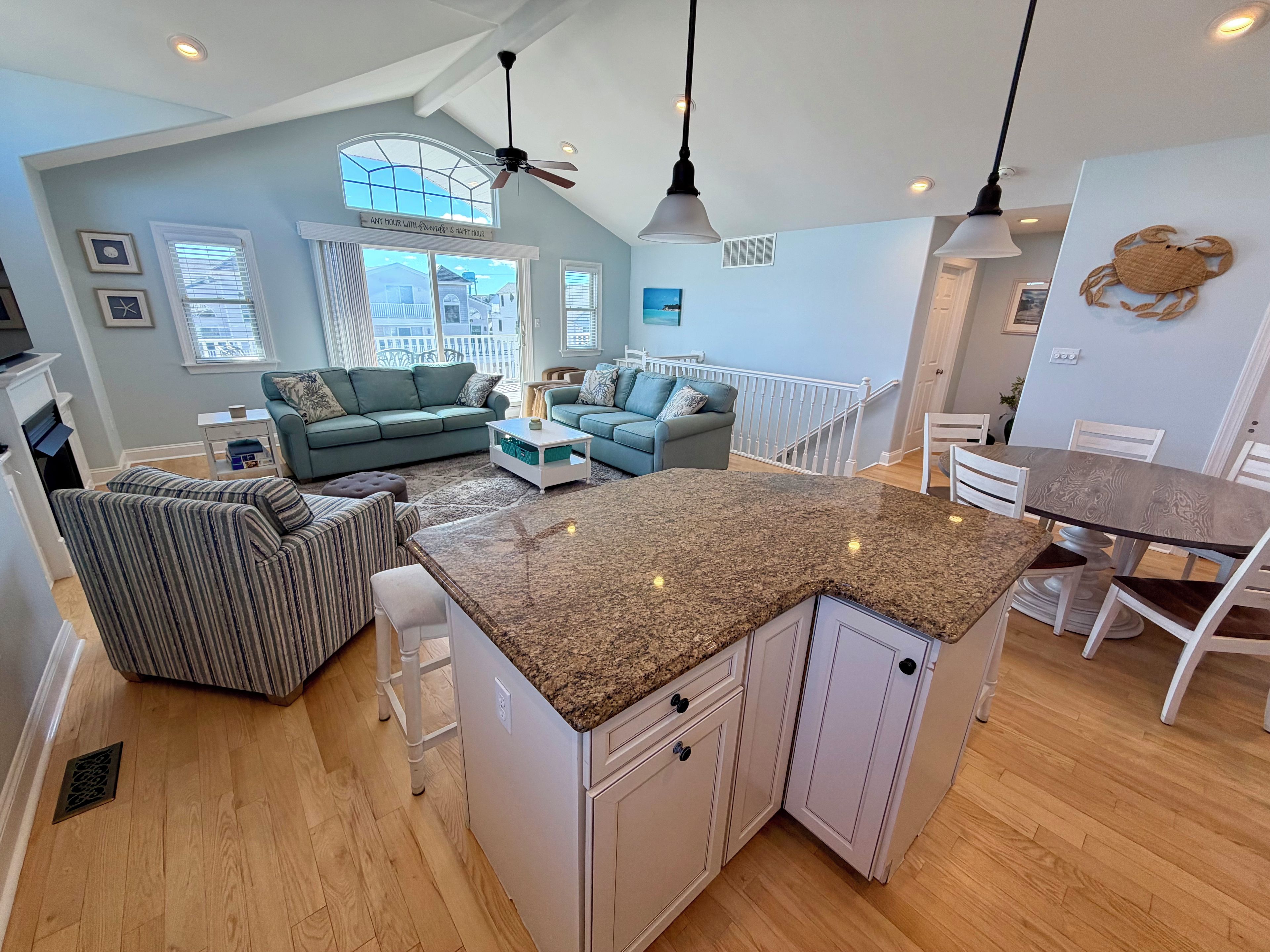 A spacious living area with a large window, a ceiling fan, and a dining area with a table and chairs.