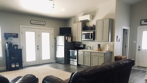 Uma cozinha moderna com armários brancos, micro-ondas e geladeira. Há uma placa na parede com a inscrição "FARMHOUSE".