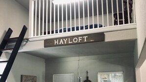 Uma área de refeições com teto alto, guarda-corpo branco e uma placa com a inscrição HAYLOFT.