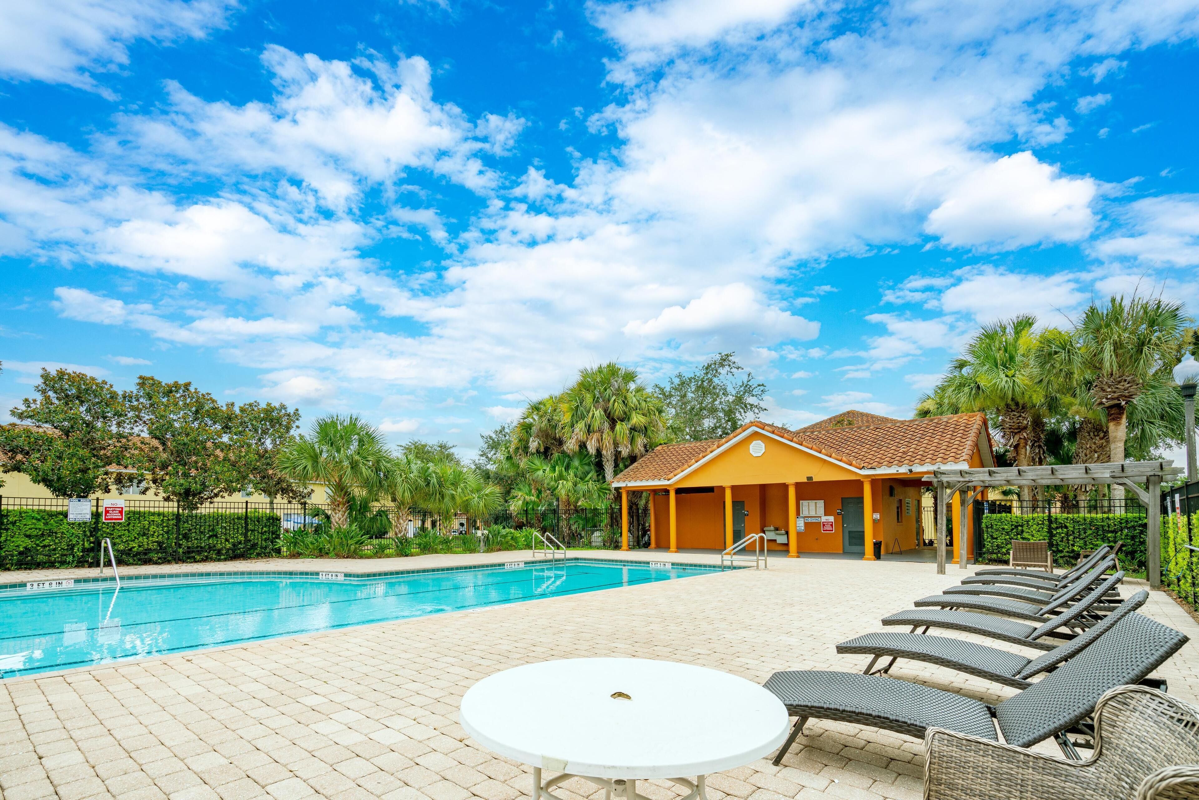 A swimming pool with lounge chairs and a small pavilion.