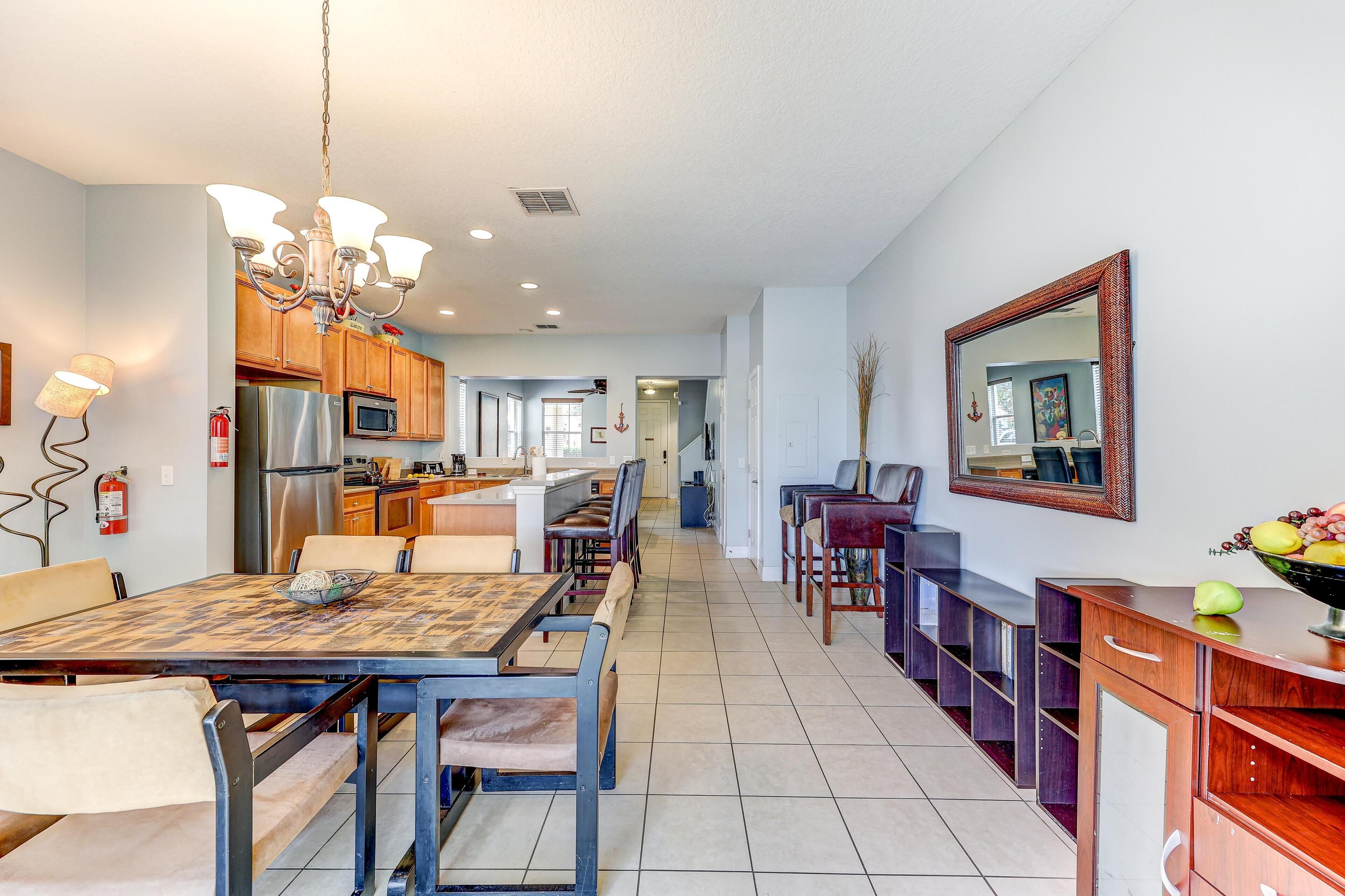 A spacious kitchen with modern appliances, a dining area with a wooden table and chairs, and a hallway leading to other rooms.