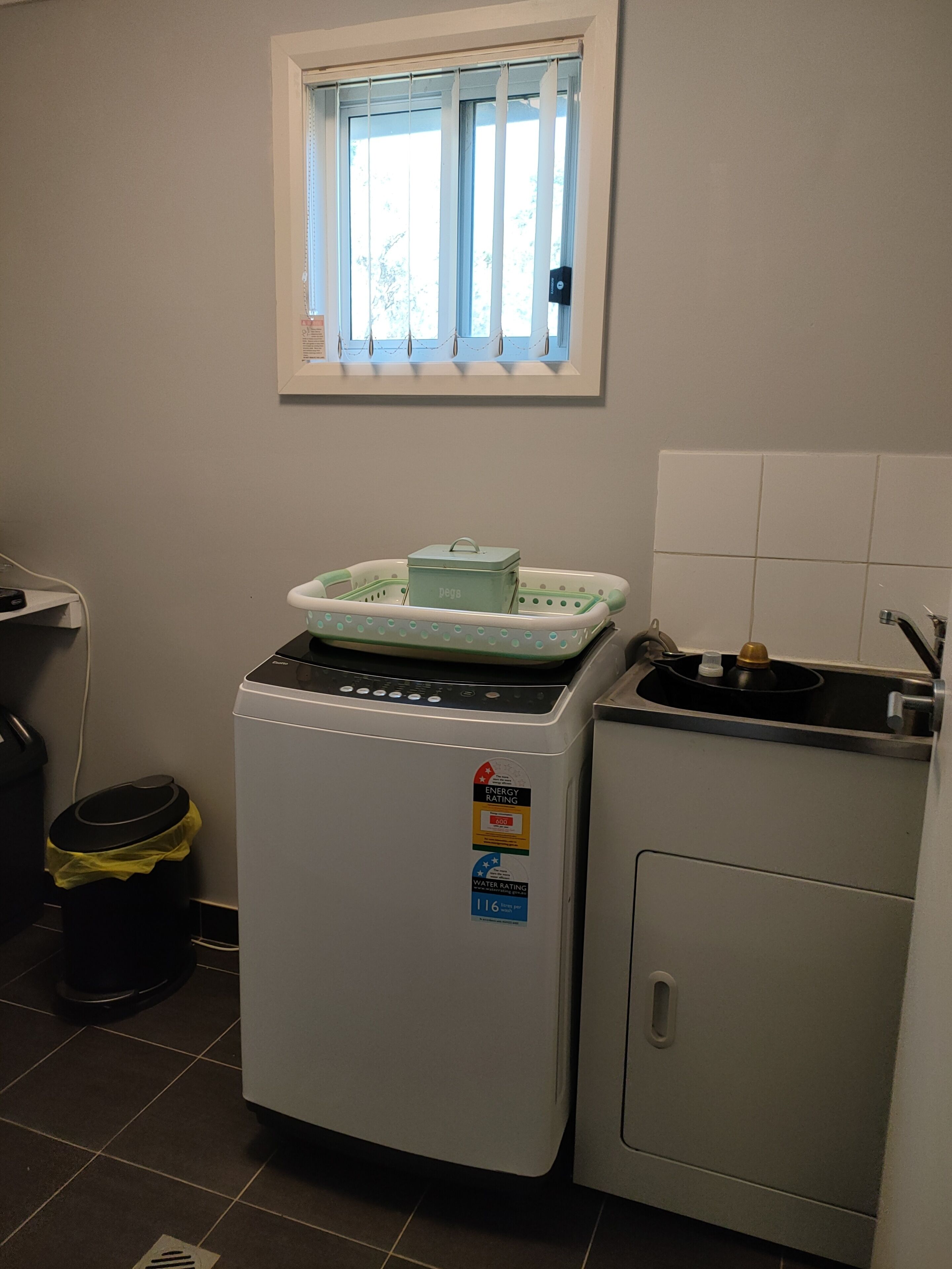 A compact kitchen with a washing machine, a small sink, and a window above the sink.