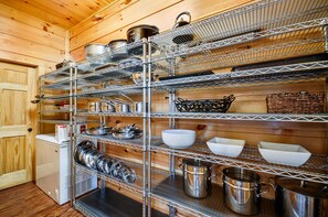 A kitchen with multiple shelves holding various kitchenware and utensils.