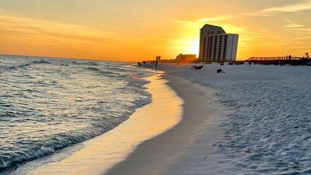A beach with footprints leading to the water, a pier, and a building in the background. - Beautiful Gulf Front Complex,White Sandy Beaches, private pool, Paradise Awaits! (Navarre)