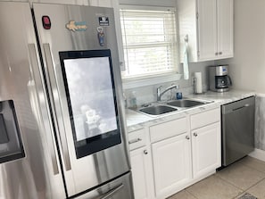 Une cuisine moderne équipée d’appareils électroménagers en acier inoxydable, d’une horloge numérique et d’une machine à café.