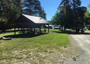 Relax in a serene natural setting beneath a rustic pavilion with picnic tables.