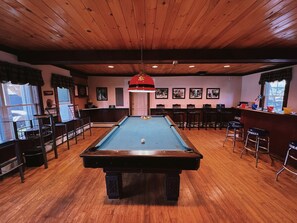Enjoy a game of pool in our billiards room, featuring a pool table and bar stools.