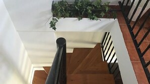 A wooden staircase with a black handrail, white walls, and a hanging green plant. - Centeno rural house, Terrace, BBQ Garden, Fireplace, wifi, Hayedo Montejo (Montejo de la Sierra)
