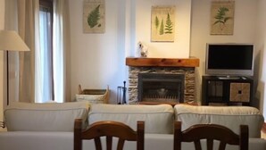 A living room with a stone fireplace, a television on a stand, and a sofa. - Centeno rural house, Terrace, BBQ Garden, Fireplace, wifi, Hayedo Montejo (Montejo de la Sierra)