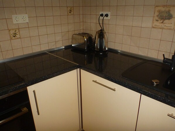 A kitchen with white cabinets, a black countertop, and a toaster. - Plovdiv Old Town 2 bedroom apartment (Plovdiv Center)