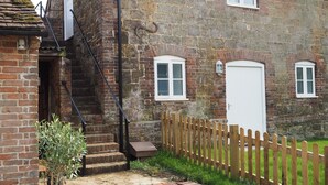 A stone building with a brick staircase, a wooden fence, and a small garden area.