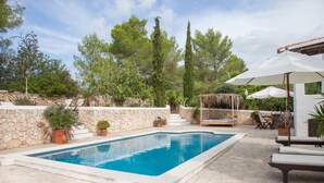 Una piscina amb parets de pedra, envoltada de plantes en testos i una escala de pedra.