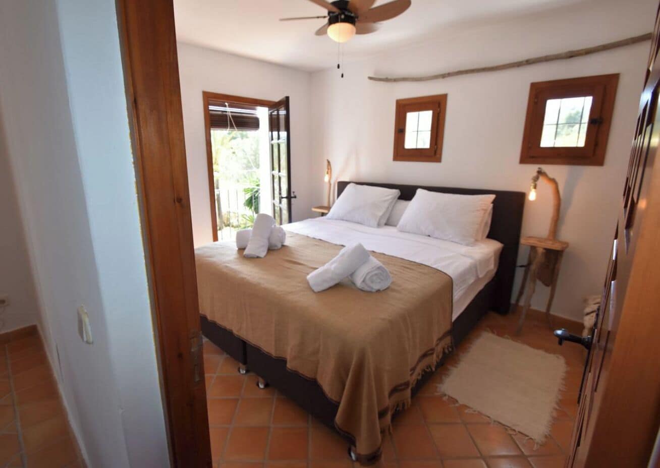 Un dormitorio con cama, ventilador de techo y ventana.