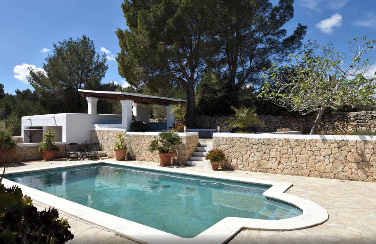 Une piscine avec un mur en pierre et une pergola.