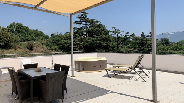 Un patio exterior con mesa y sillas, un jacuzzi y una pérgola.