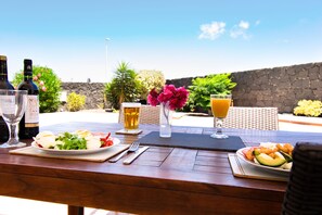 Enjoy a meal al fresco with a table set amidst lush greenery and a stone wall.