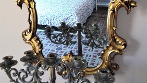 Une chambre à coucher comprenant un lit, des tables de chevet, une lampe et un miroir avec un cadre doré orné.