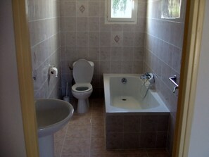A bathroom with a toilet, sink, and bathtub. - Studio on on a flowered land of 3000 square meters, view on the mountain (Calvi)