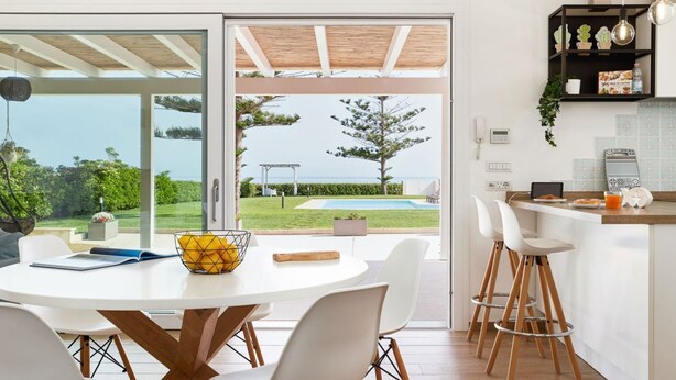 A modern kitchen with a large window overlooking a pool and garden. - Sea Home - Villa with pool by the sea (Marina di Modica)