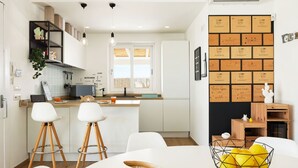 A modern kitchen with white cabinets, a central island, bar stools, and a fruit bowl. - Sea Home - Villa with pool by the sea (Marina di Modica)
