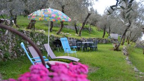 Un espace jardin aménagé avec des sièges extérieurs, comprenant une table et des chaises, sous un parasol coloré.