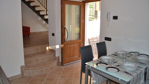 Un coin repas avec une table dressée pour quatre personnes, un escalier et une porte en bois.