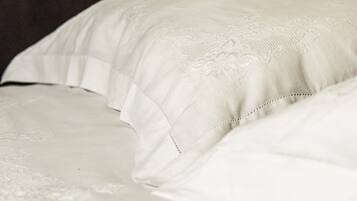 A close-up of a bed with a white, textured bedspread and pillows.
