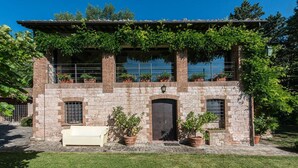 A stone building with a wooden balcony, potted plants, and a bench. - CHARMING FARMHOUSE IN THE MARCHIGIAN HILLS (Fabriano)