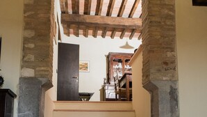 A staircase with a brick archway leading to a room with a wooden ceiling and a door. - CHARMING FARMHOUSE IN THE MARCHIGIAN HILLS (Fabriano)