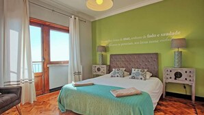 A bedroom with a bed, two bedside tables, a window with curtains, and a wall with a quote. - APOLONIA 4 FRONTAL. In the center of the monumental Lisbon  (Lisboa)