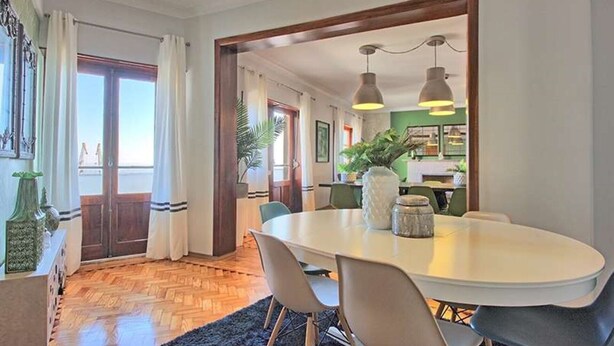 A dining area with a round table, chairs, and pendant lighting. There is a view into the kitchen area with a green wall and a potted plant. - APOLONIA 4 FRONTAL. In the center of the monumental Lisbon  (Lisboa)