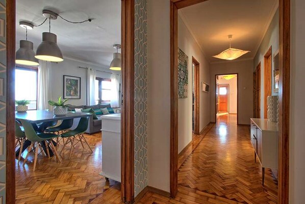 A spacious hallway with wooden flooring, a dining area with a table and chairs, and pendant lighting.