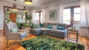 A modern living room with a sofa, armchairs, and a coffee table. There are pendant lights, a rug, and a view of the outside through large windows. - APOLONIA 4 FRONTAL. In the center of the monumental Lisbon  (Lisboa)
