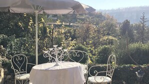 An outdoor seating area with a round table, two chairs, and a decorative candelabra. - Three Levels -2 Bedroom-2 Bathroom-alfresco Terrace-fully Renovated (Saignon)